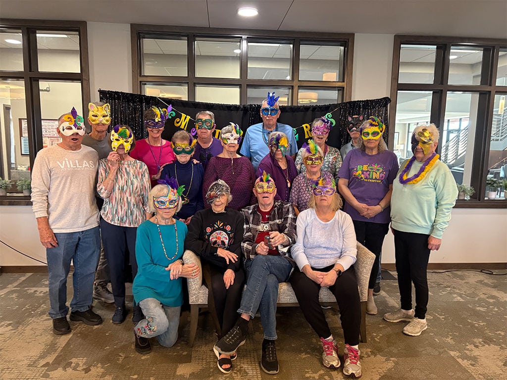 Residents at Villas at Stoney Point enjoying the annual Mardi Gras event with handmade masks, beads and colorful decorations.
