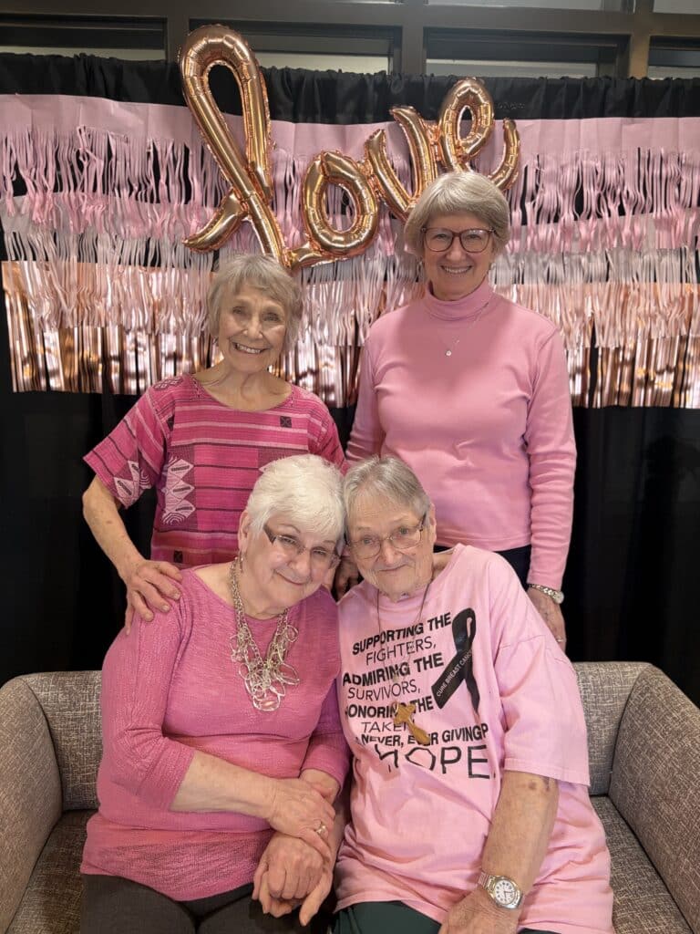 Residents dressed in pink and red posing in front of a “Love” backdrop during Villas at Stoney Point’s Galentine’s Day celebration.
