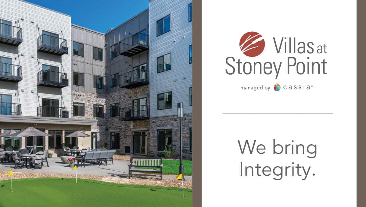 Villas at Stoney Point senior living community courtyard with patio seating, putting green, and modern apartment building with balconies in Minnesota, managed by Cassia.