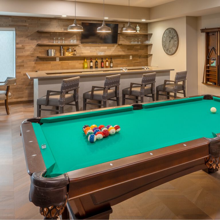 Game room with billiards table, bar seating, wall-mounted television, and shelving in a social lounge space at Villas at Stoney Point