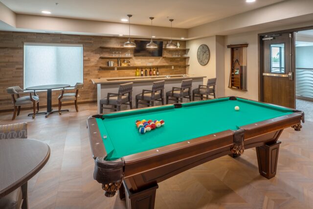 Game room with billiards table, bar seating, wall-mounted television, and lounge tables at Villas at Stoney Point
