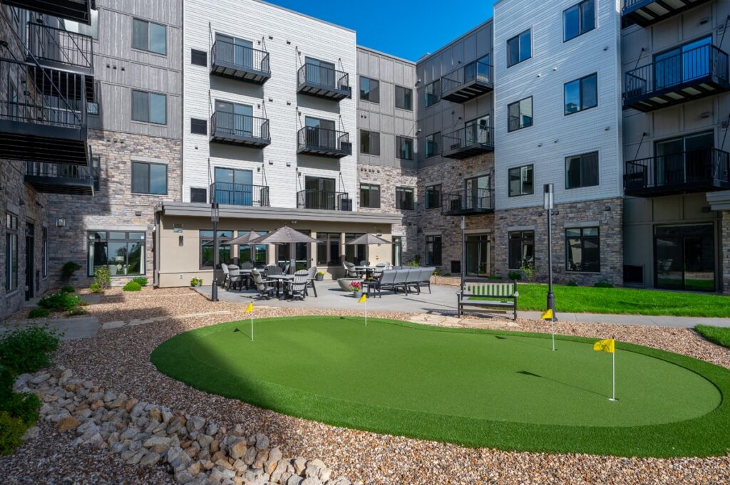 Courtyard with putting green, outdoor seating, benches, and surrounding apartment building with balconies at Villas at Stoney Point