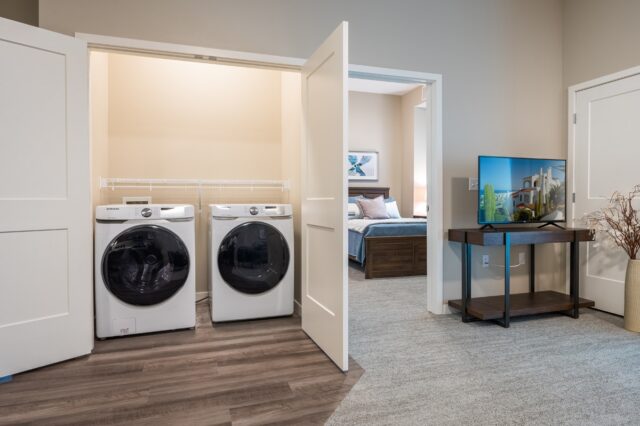 Apartment laundry area with washer and dryer located in a closet space near a bedroom at Villas at Stoney Point