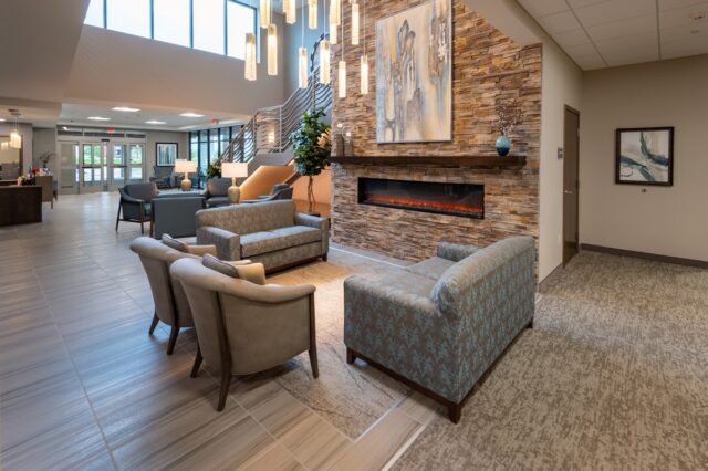 Lobby seating area with sofa, armchairs, large stone fireplace, pendant lighting, and open entry space at Villas at Stoney Point
