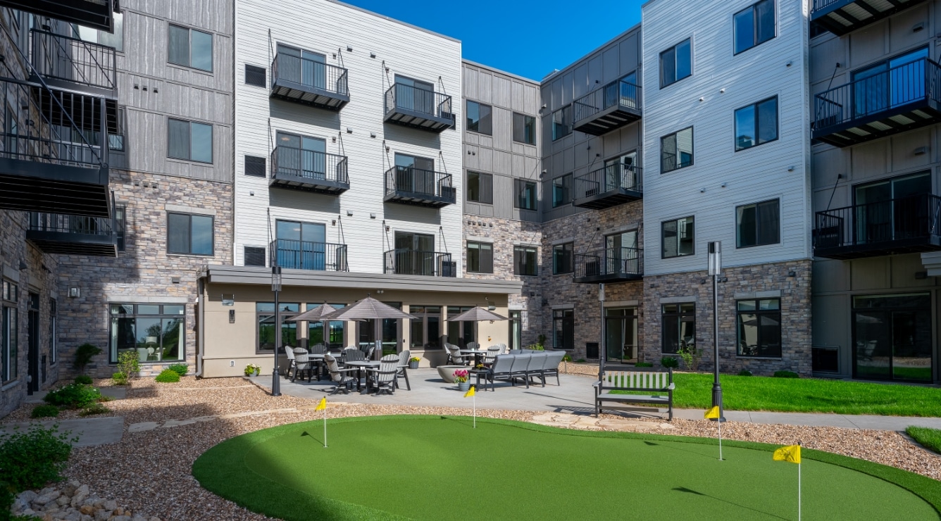Courtyard with putting green, outdoor seating, umbrellas, and surrounding apartment building at Villas at Stoney Point