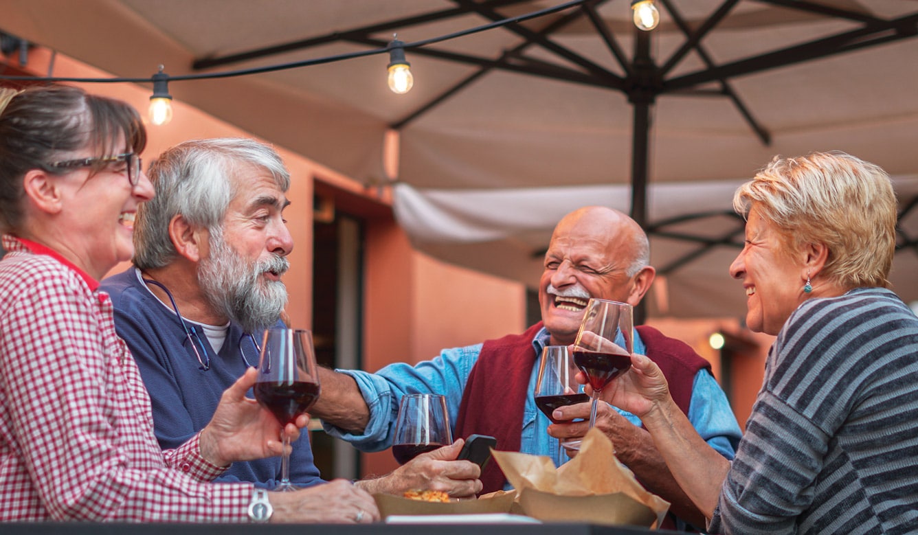 Group of adults gathered outdoors holding drinks and socializing at a table, representing social lifestyle and community connection like Villas at Stoney Point