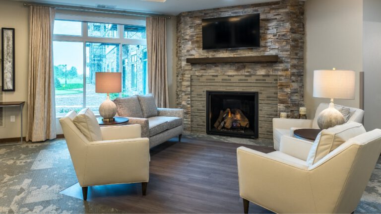Comfortable lounge area with armchairs, sofa, stone fireplace, and large windows at Villas at Stoney Point