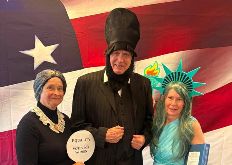 Residents dressed as historical figures pose in front of an American flag backdrop during the America 250 celebration at Villas at Stoney Point.