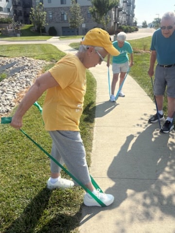 Resident stretching with a resistance band during an outdoor exercise session.