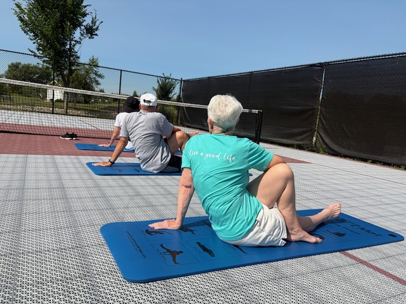 Residents stretching on exercise mats during an outdoor fitness class.