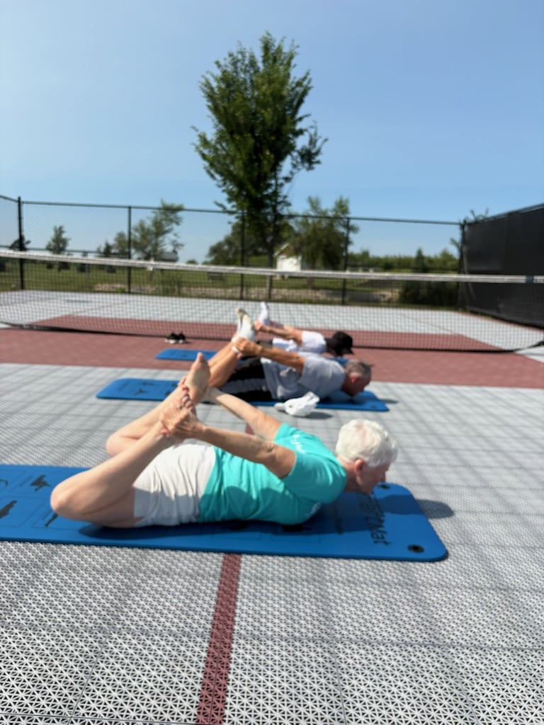 Residents stretching on exercise mats during an outdoor fitness class.